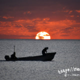 水平線に隠れる太陽と漁船