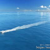 鏡のような青い海を走るボート