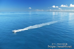 鏡のような青い海を走るボート