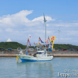大漁旗を掲げて青い海を走る漁船-狩俣海神祭