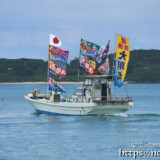大漁旗を掲げて青い海を走る漁船-狩俣海神祭