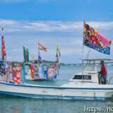 大漁旗を掲げて青い海を走る漁船-狩俣海神祭