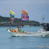 大漁旗を掲げて青い海を走る漁船-狩俣海神祭