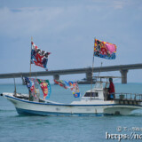 大漁旗を掲げて青い海を走る漁船-狩俣海神祭