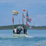 大漁旗を掲げて青い海を走る漁船-狩俣海神祭